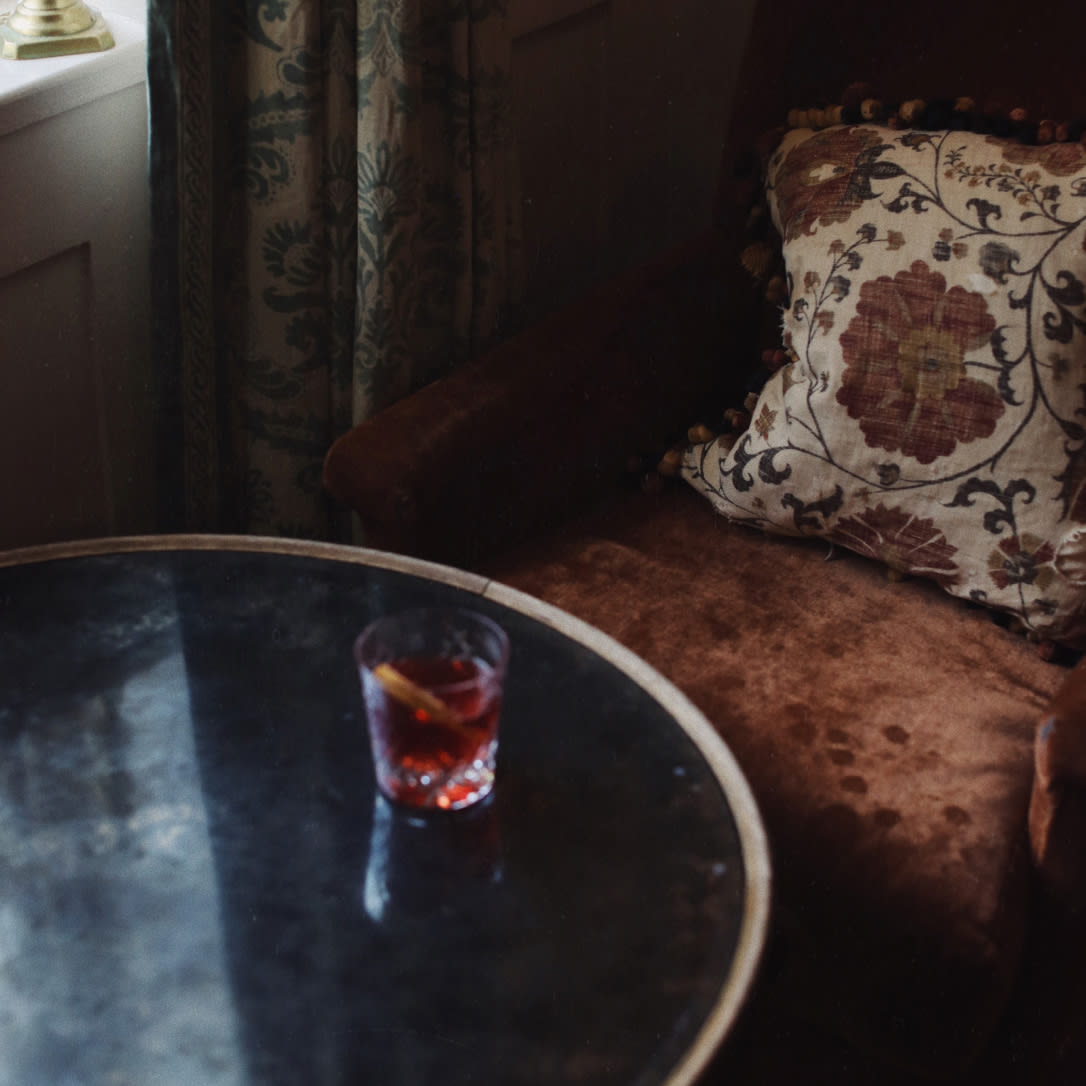 A cocktail on a table in a dark corner of a room.