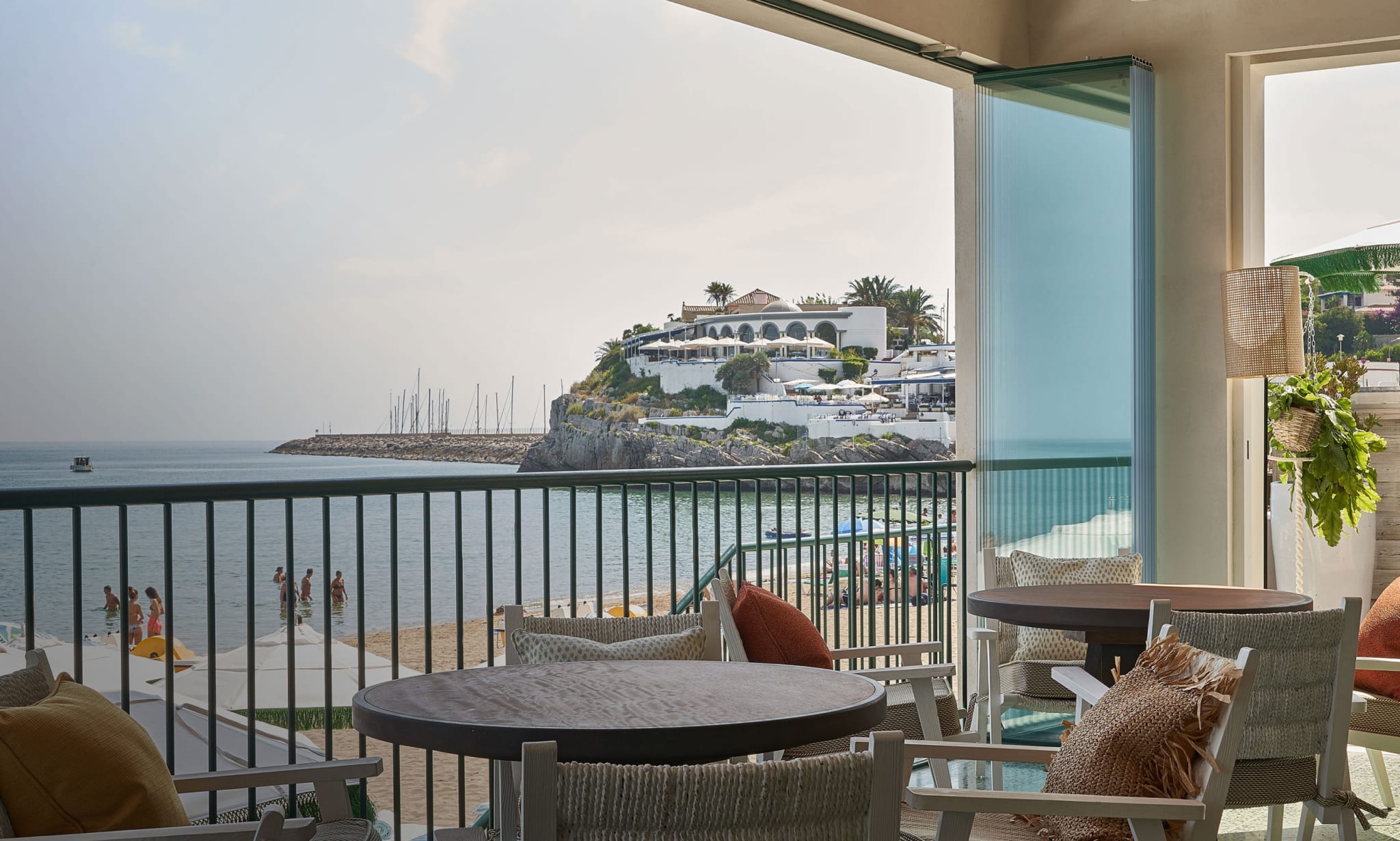 An indoor seating area looking over a beach and the sea.