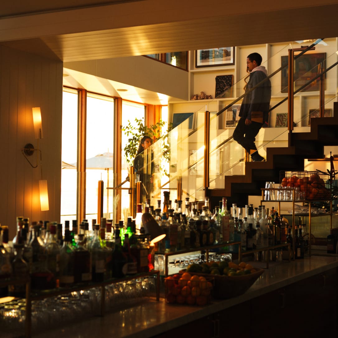 Two people walking down stairs into a bar area.