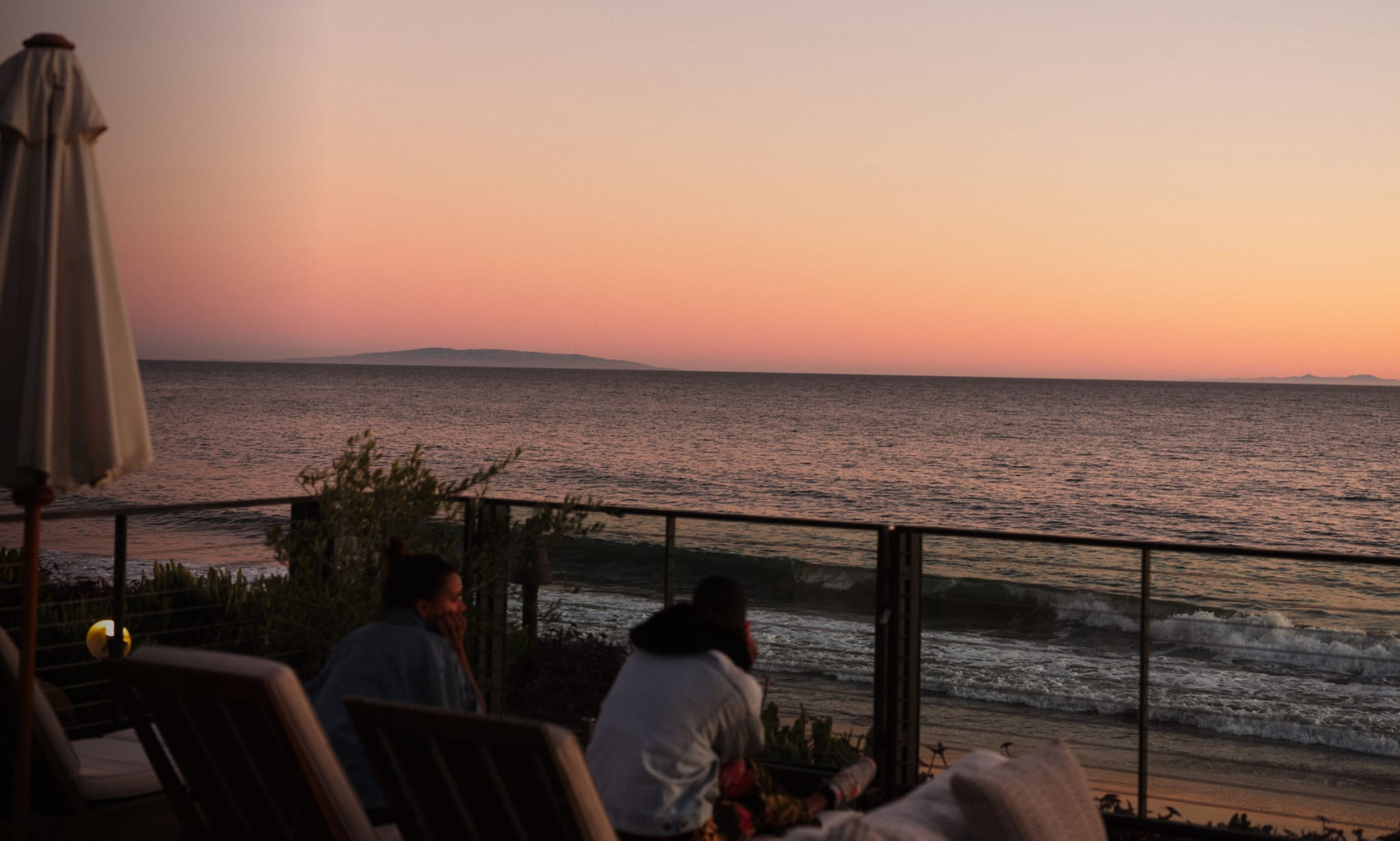 Two people on loungers on a terrace overlooking the sea.