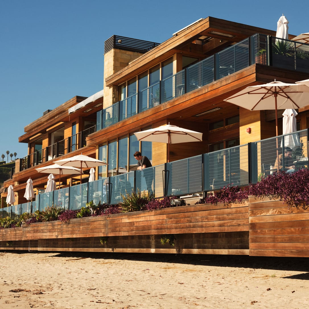 A man standing on a terrace outside a beachhouse.