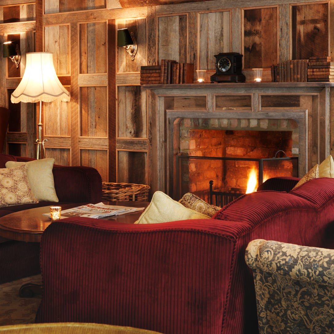 Sofas and chairs around a fireplace in a wood panelled room.