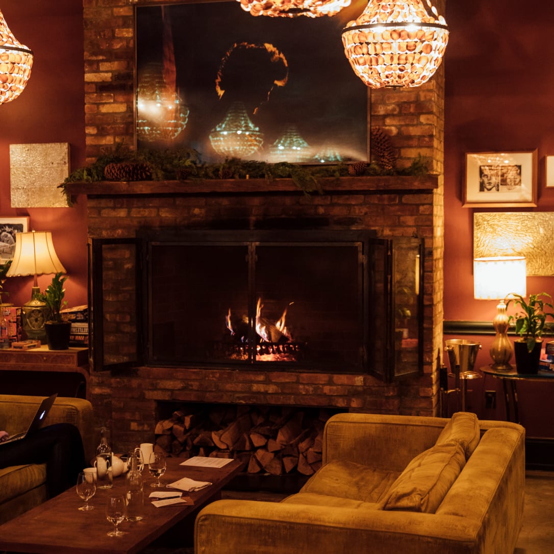 A fire burns in a cosy space full of soft furnishings.