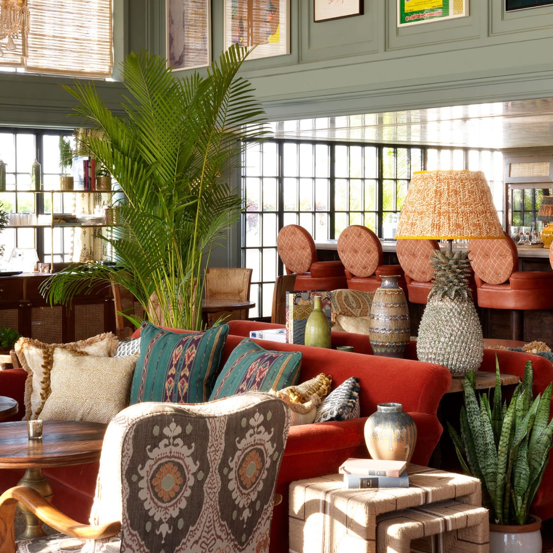 A green bar interior with various chairs tables and plants.