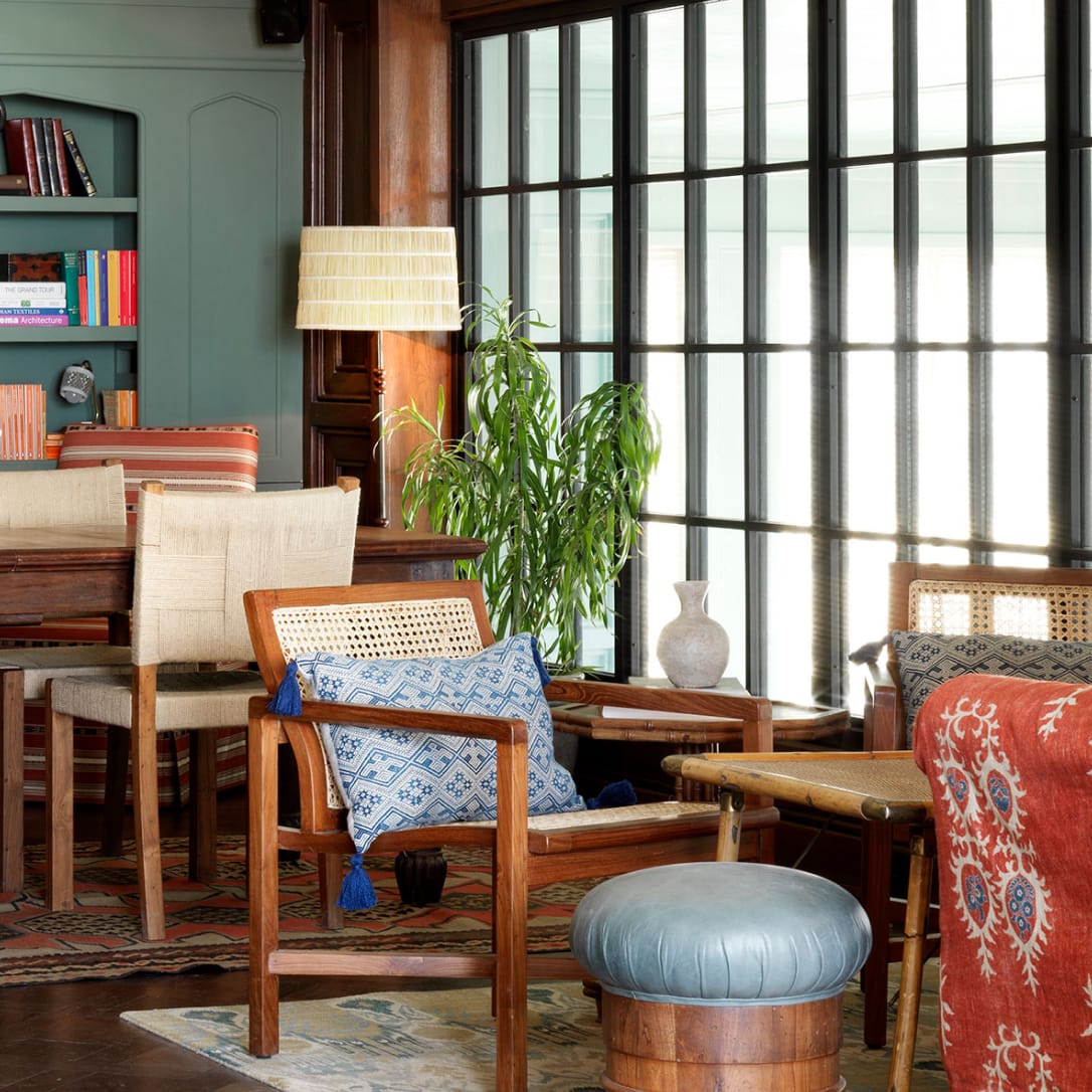 A small interior with floor to ceiling windows and various chairs and tables.
