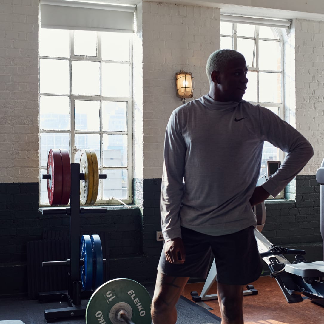 A man rests while lifting weights in a gym.