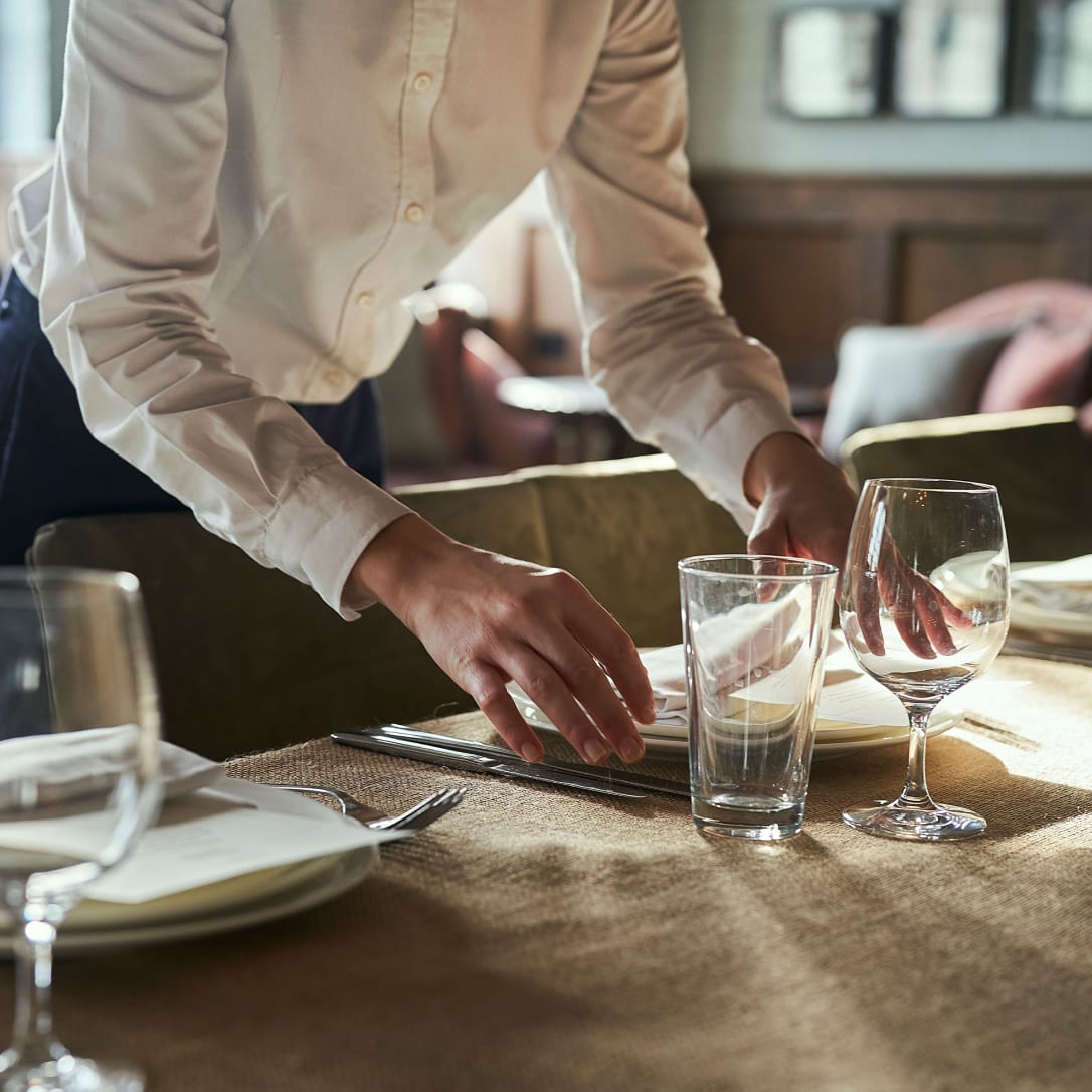 A person laying a table for a formal dinner.