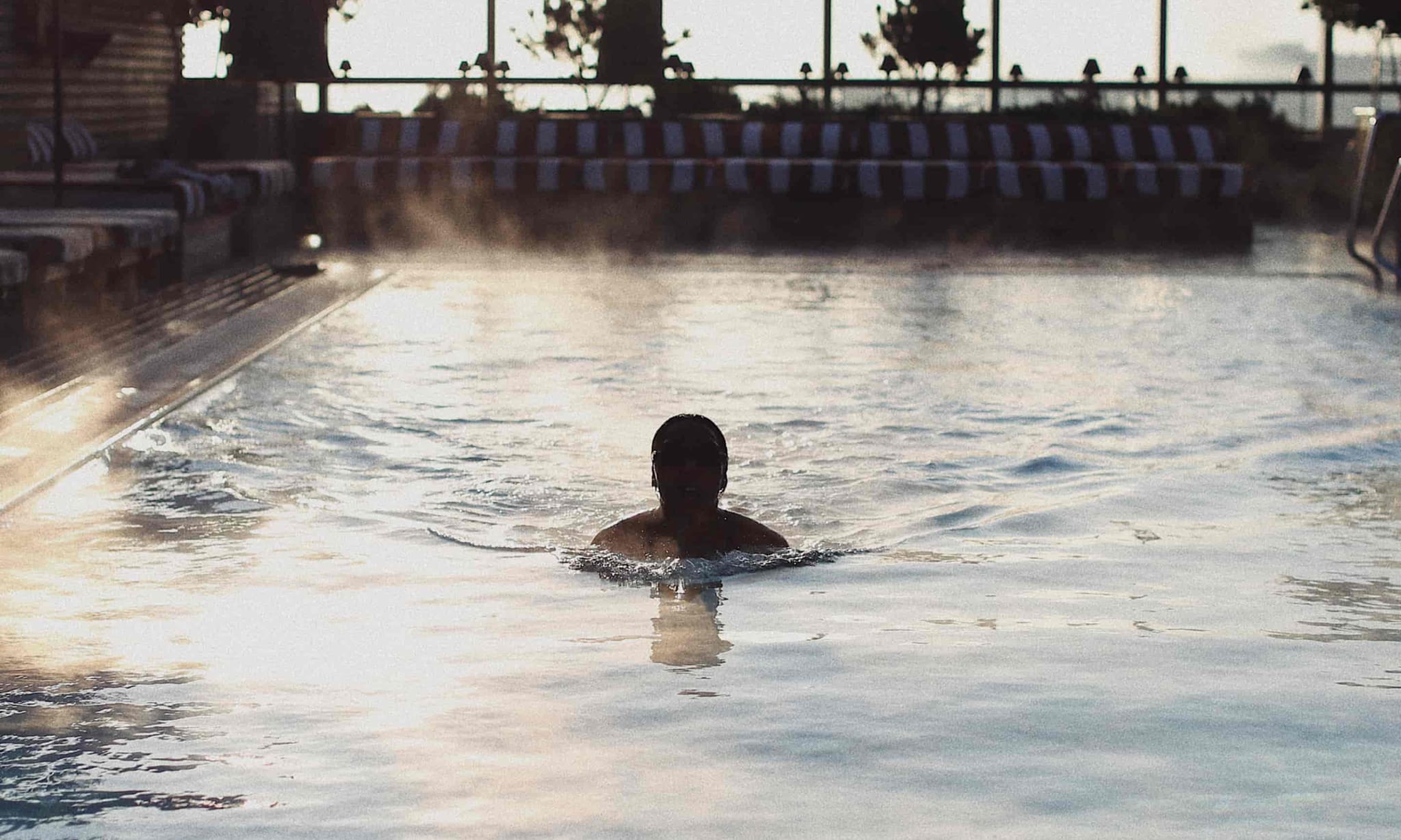 A man swims in a rooftop pool.