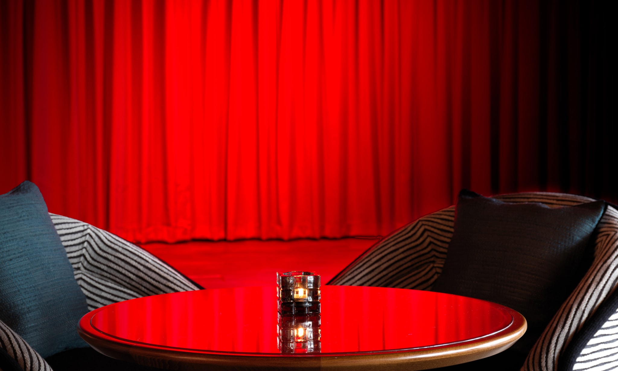 A stage is bathed in red light by a table and chairs.