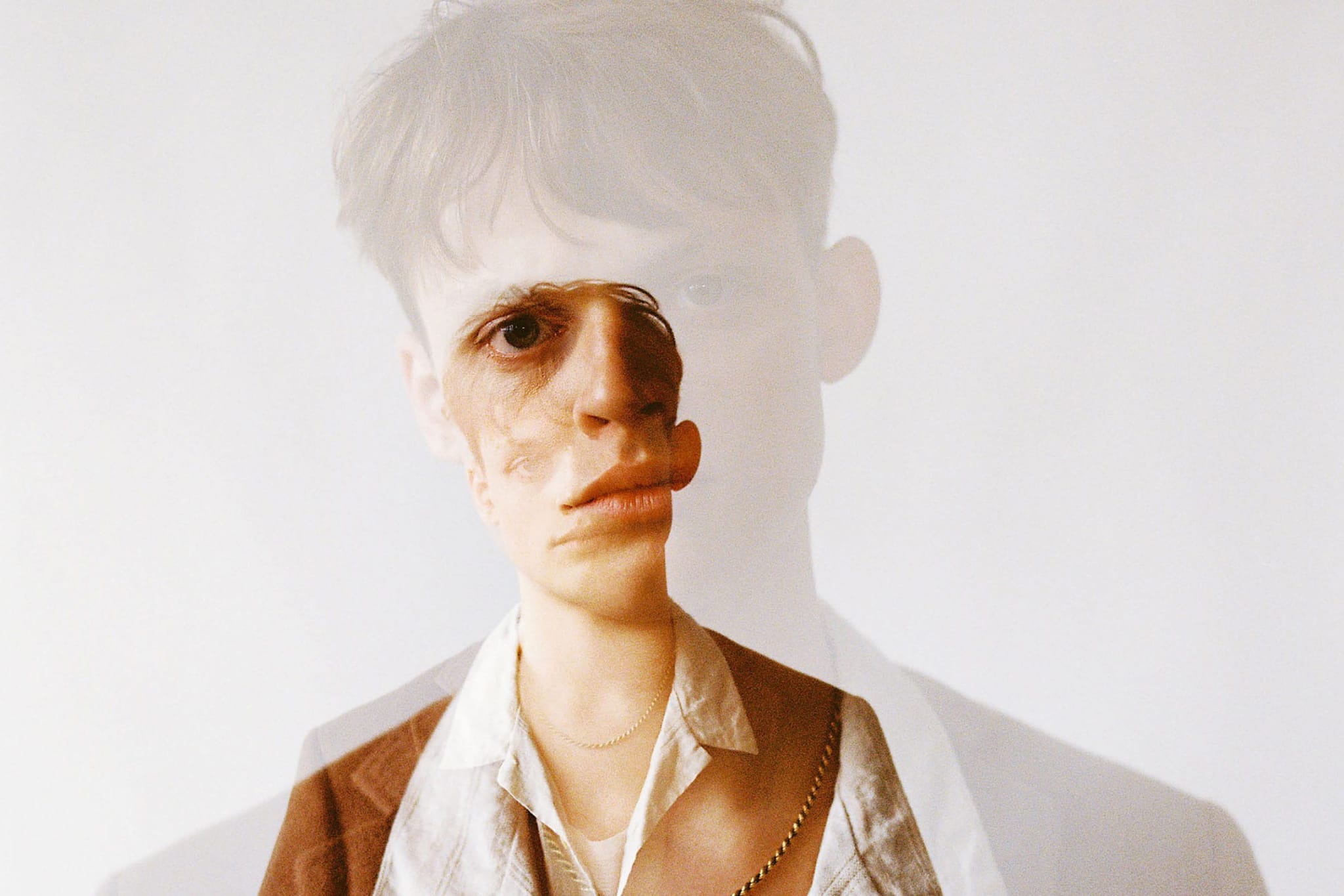 A double exposure of a young man wearing a seventies style shirt and jacket.