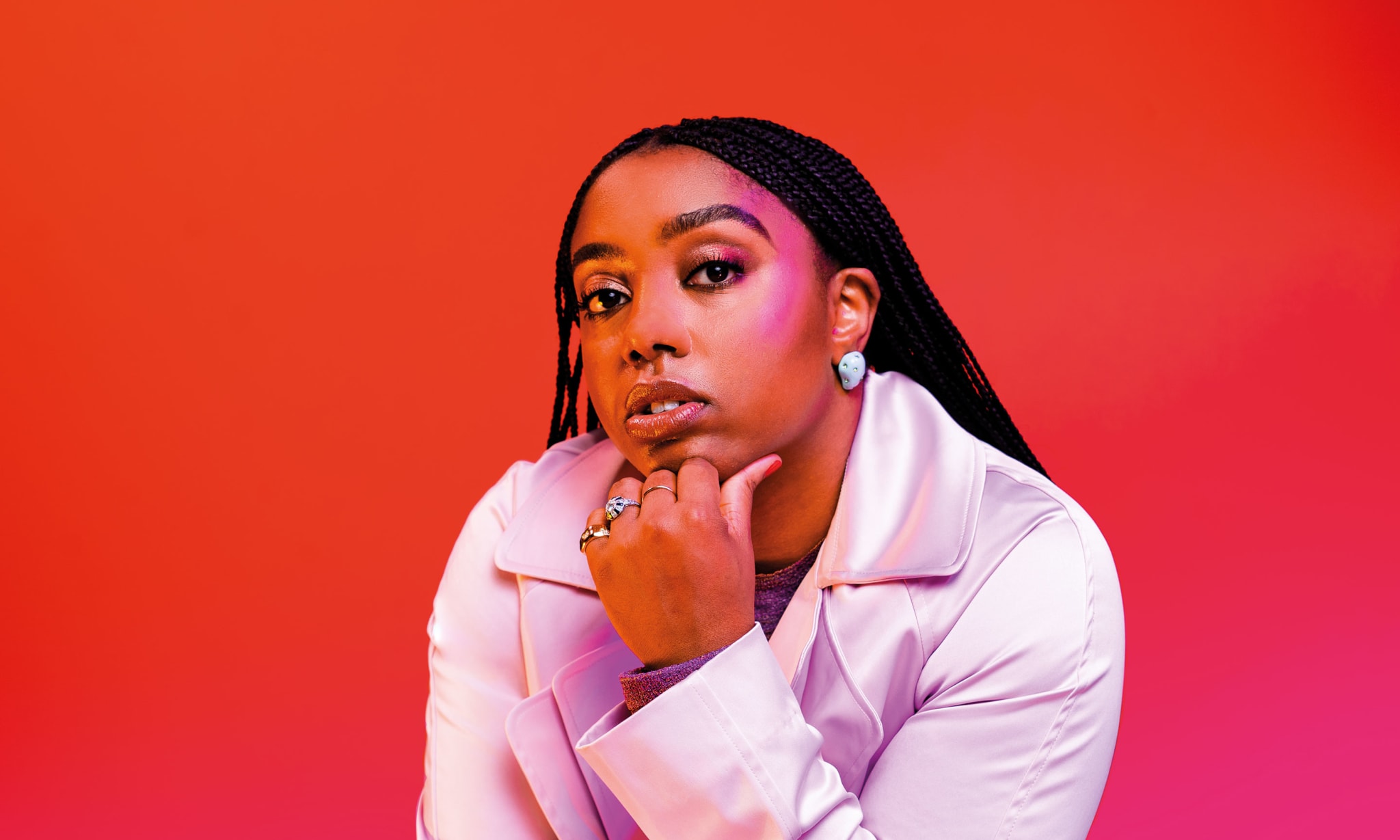woman in white jacket against red background with head resting on hand