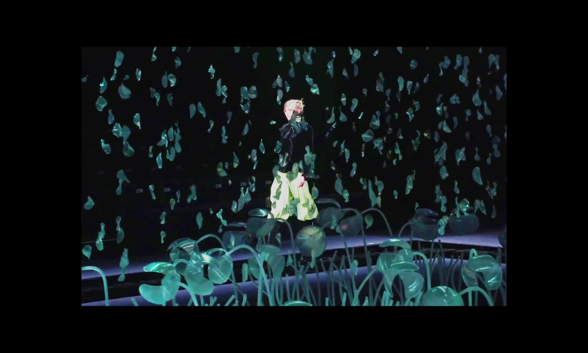 A model walking during a catwalk show in a dark room with no audience.