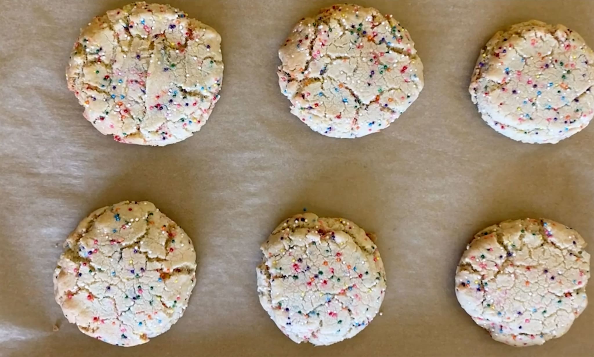 Six cookies with colourful sprinkles in them.