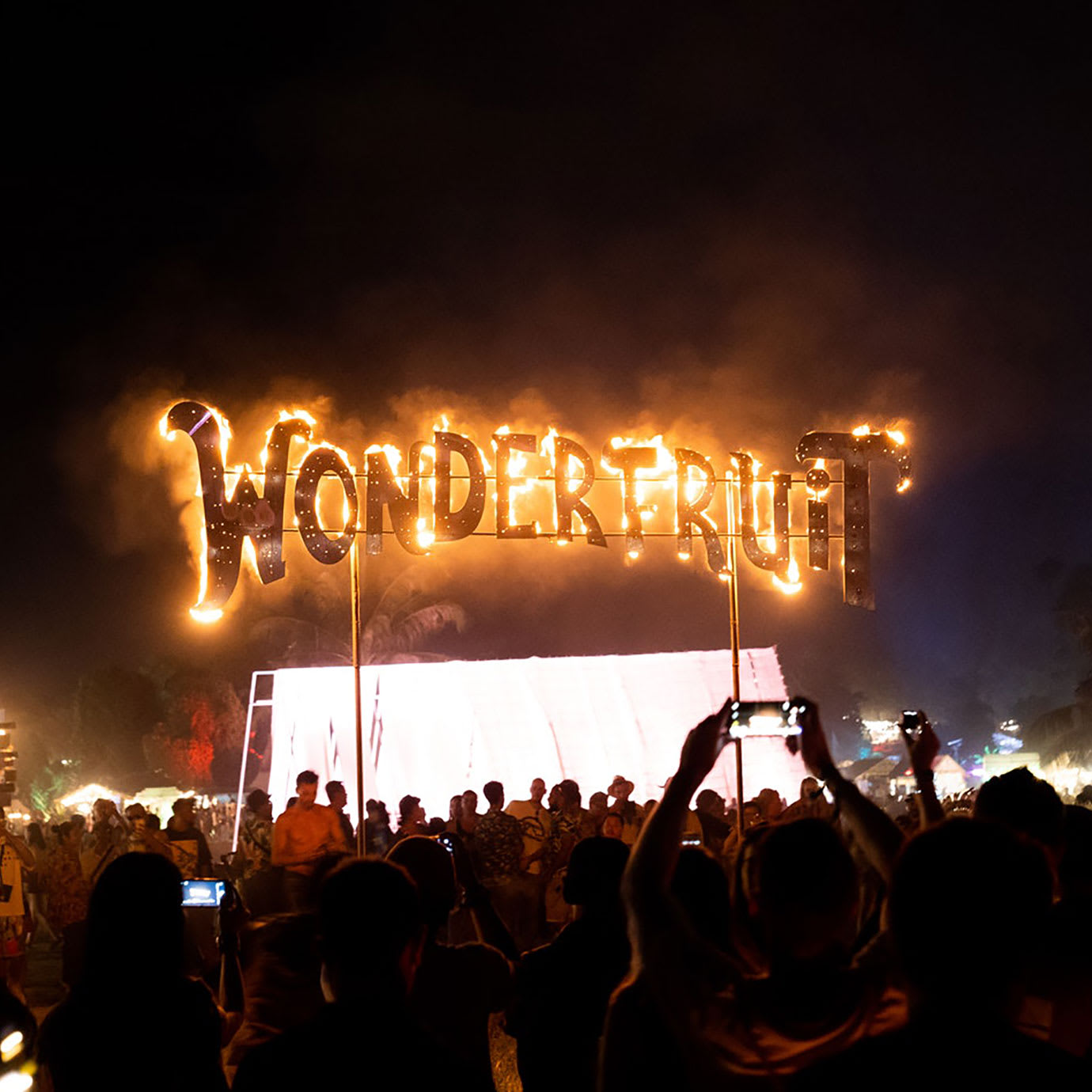 A crowd around a sign with Wonderfruit written in fire on it.