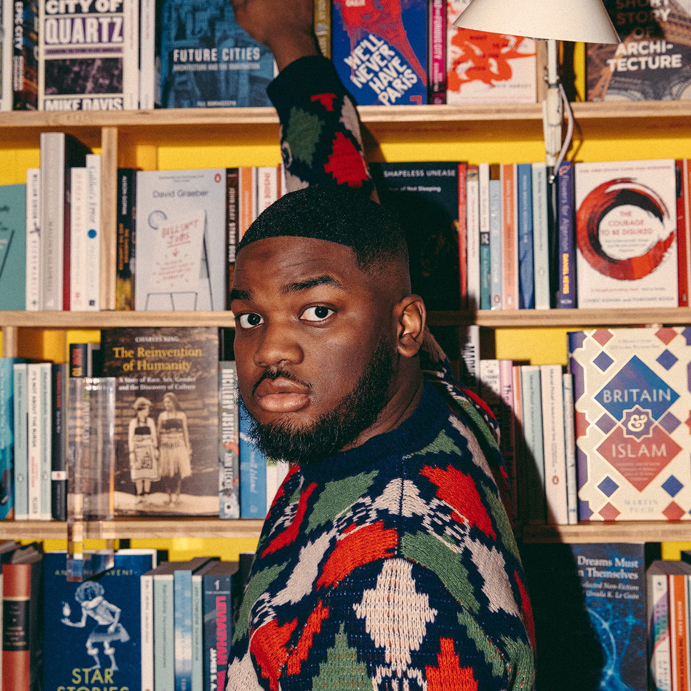 A man by a bookshelf.