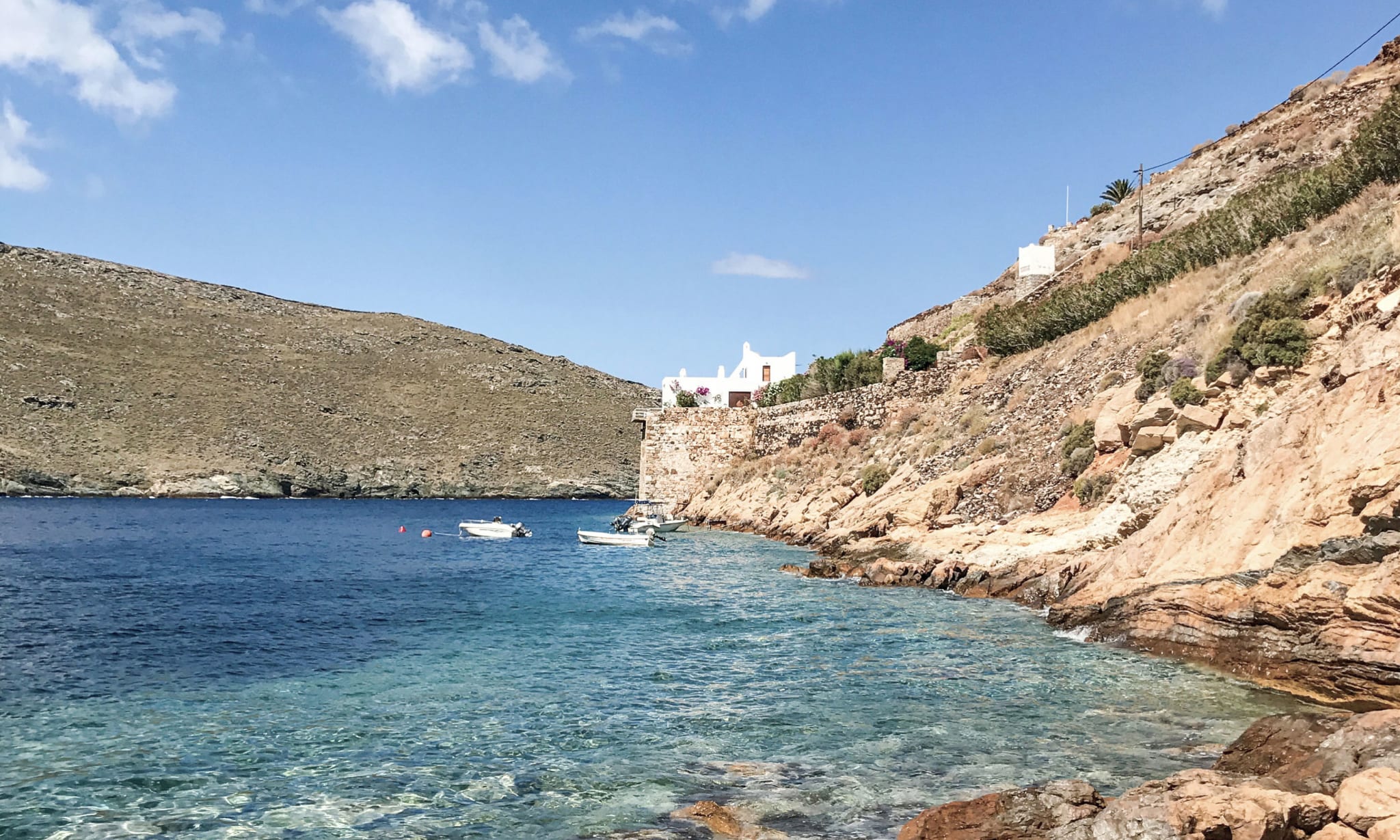 A bay with cliffs going up to a white house.