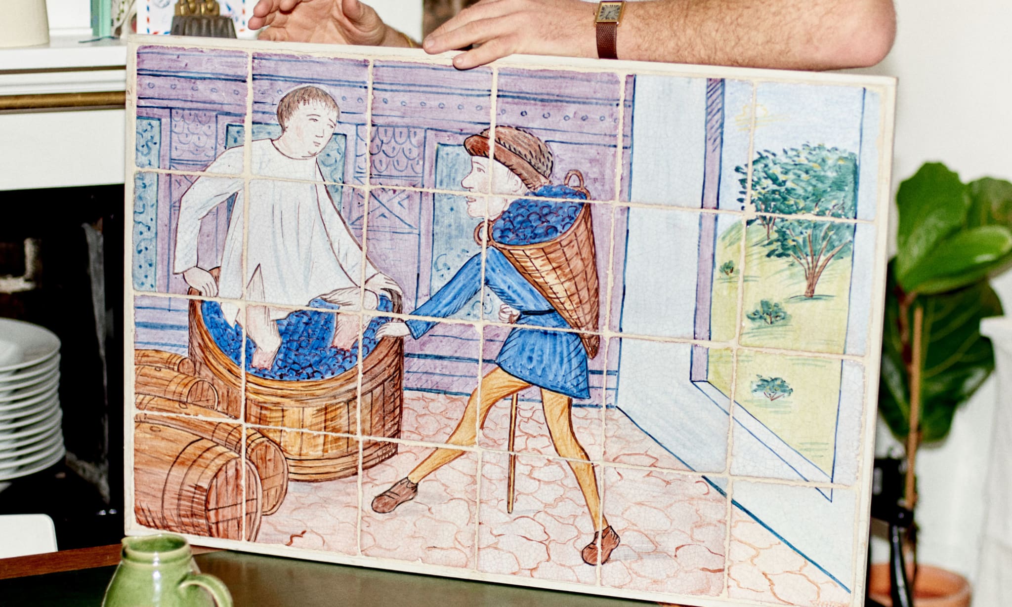A man holding a painting on tiles.