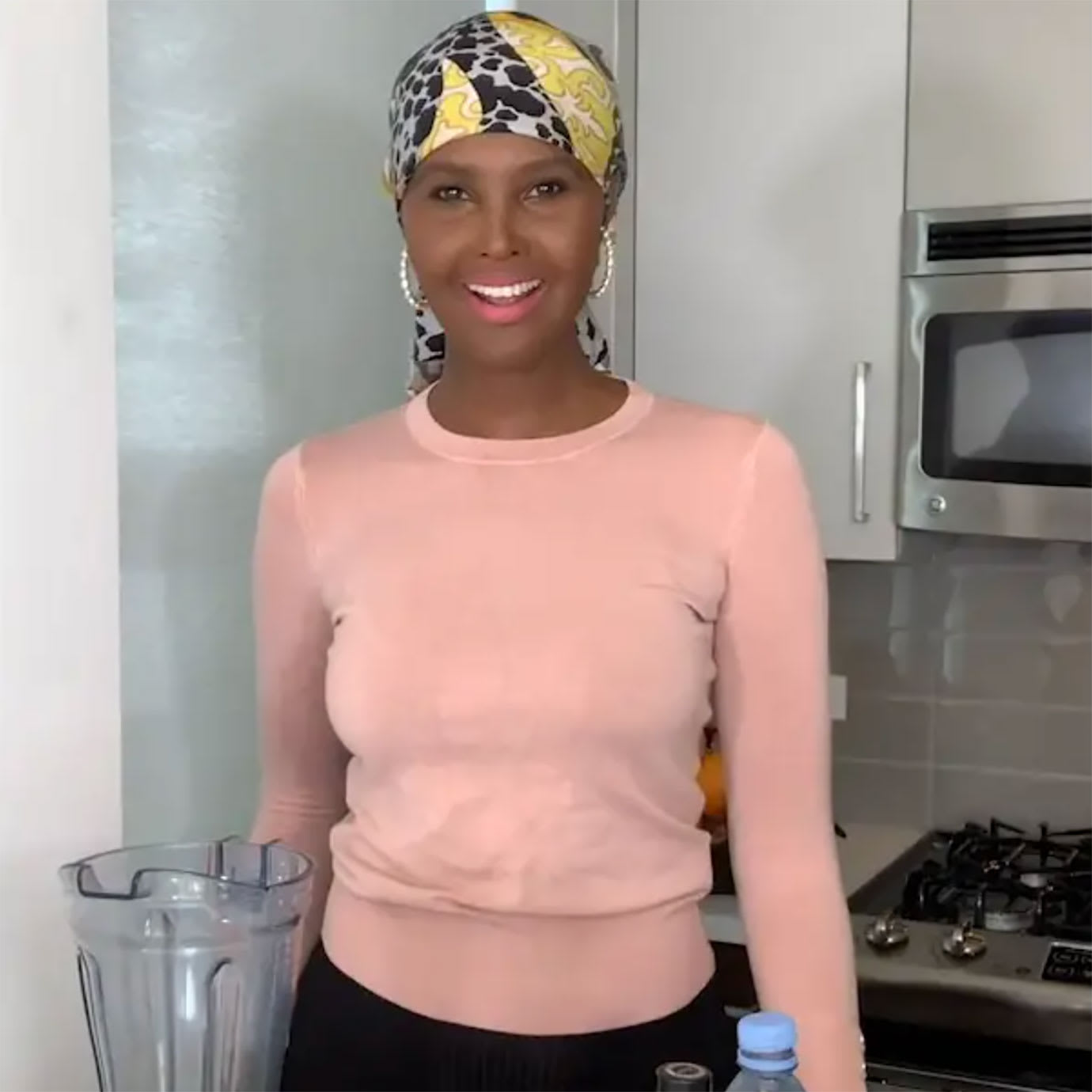 A woman standing in a kitchen next to a blender.