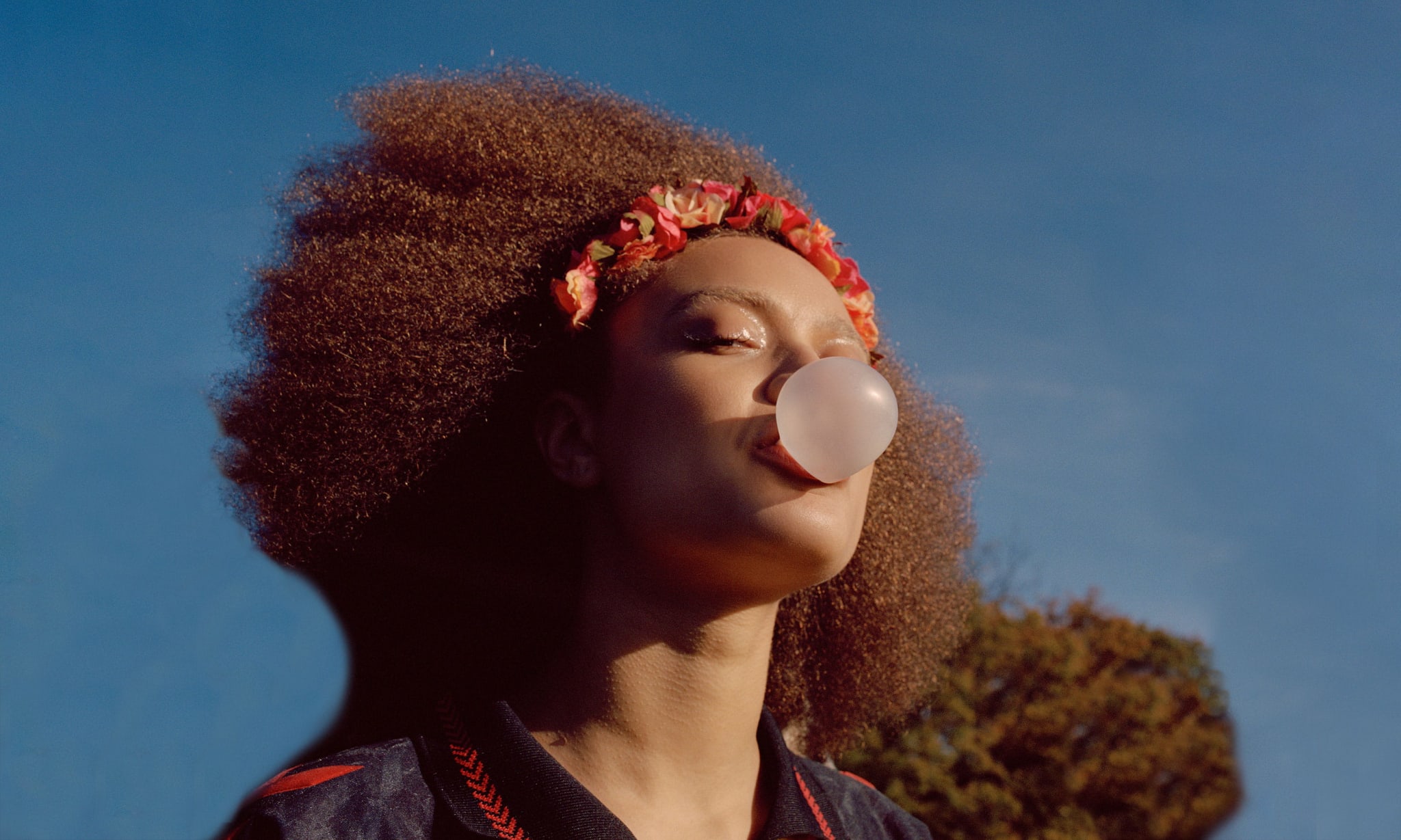 A woman blowing a large pink bubble with gum.