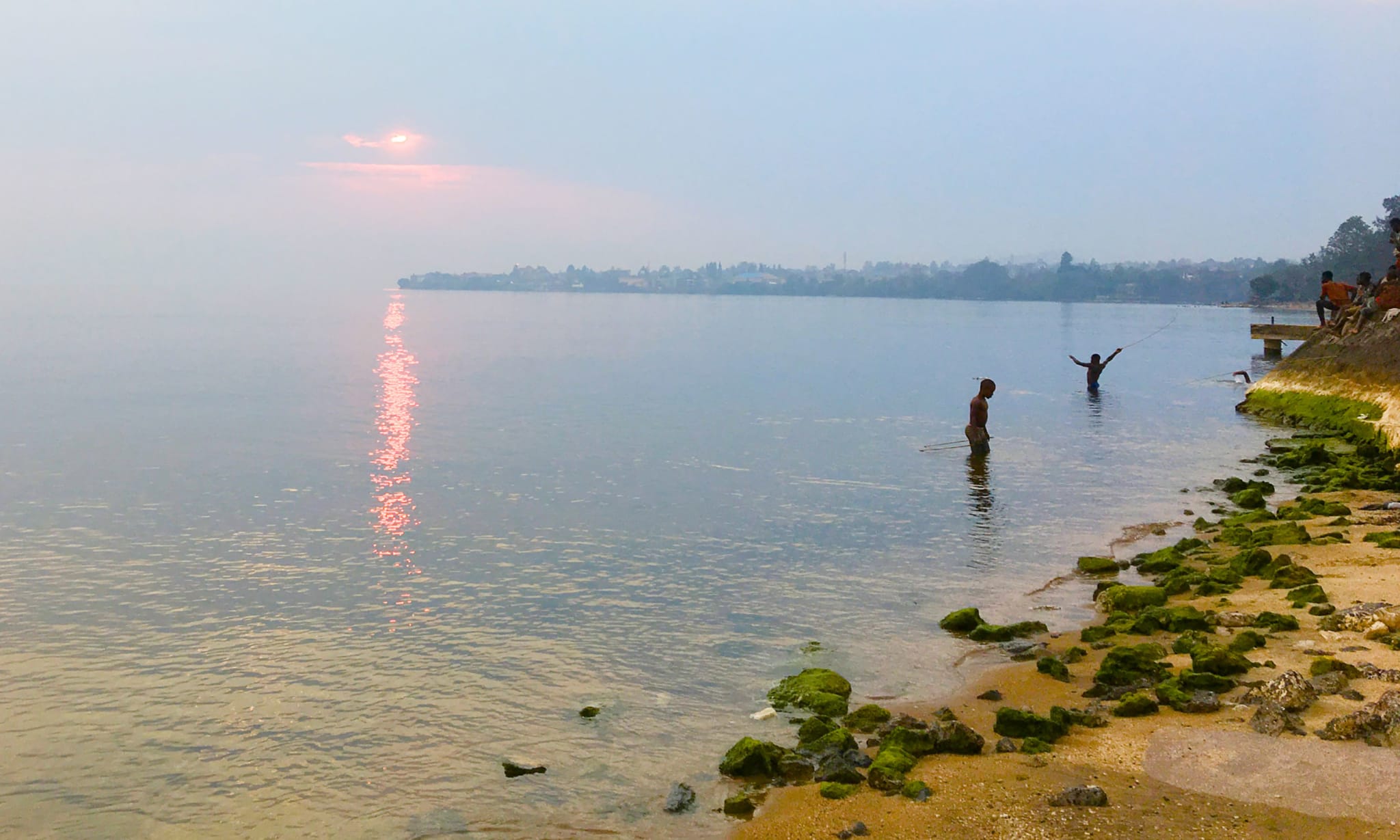 Two people playing in a lake at sunset.