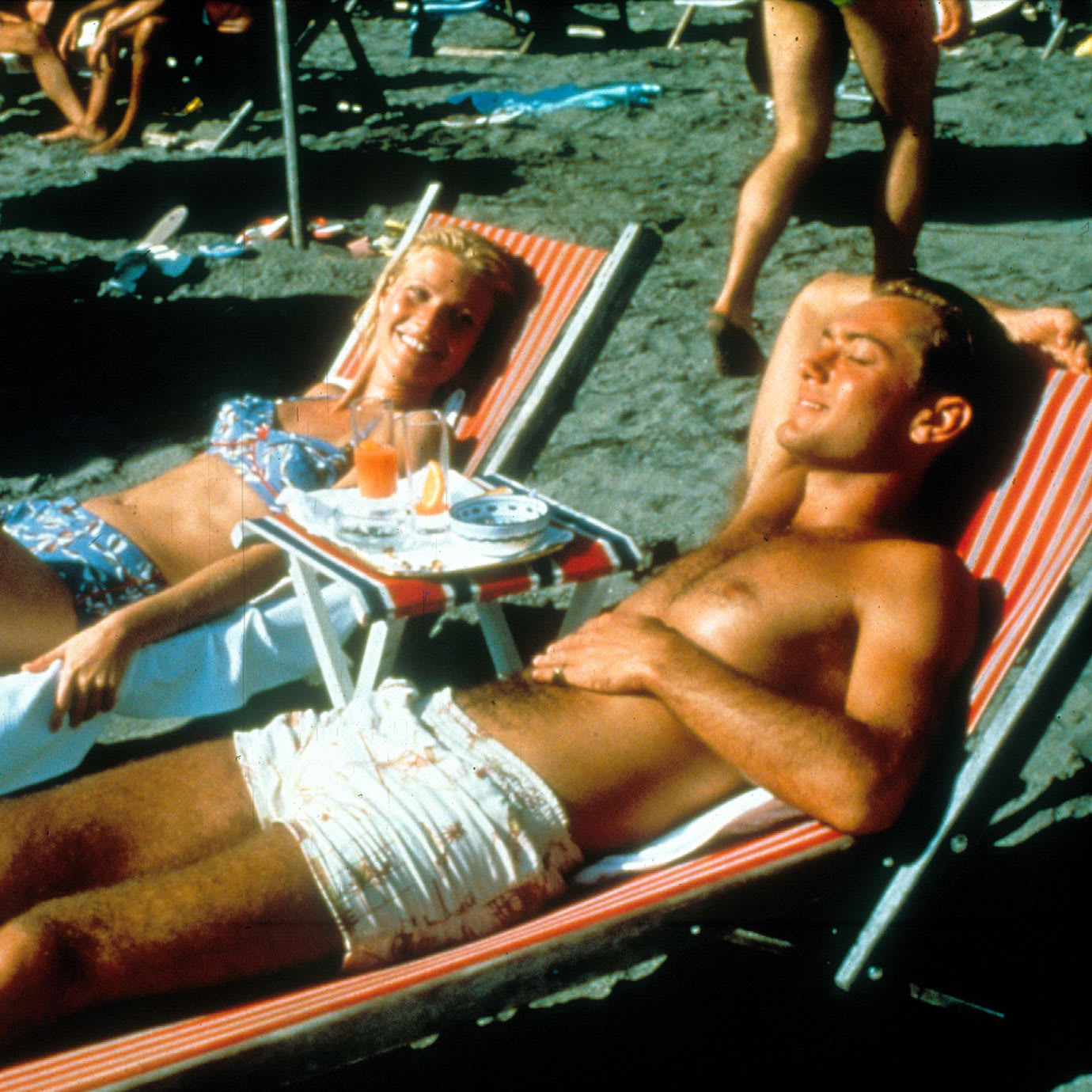 A man and a woman sunbathing on a beach.