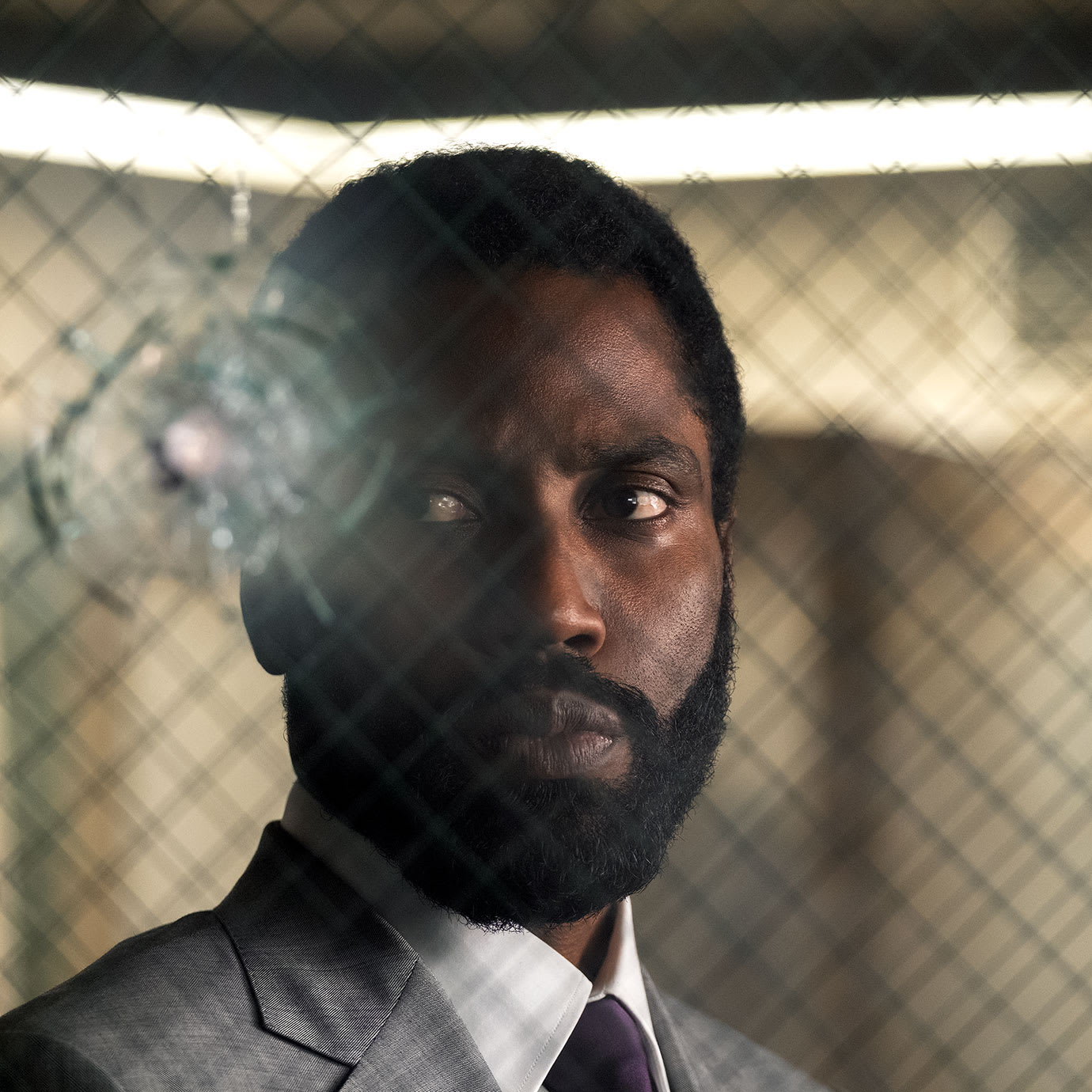 A man standing behind a window with a bullet hole in it.