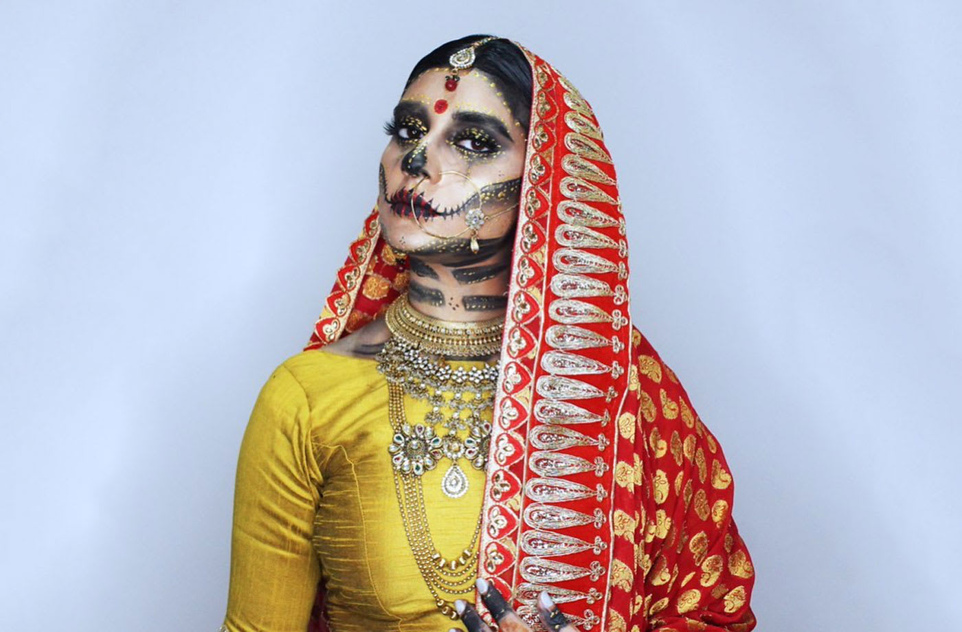 A young model dressed in a sari with her face painted like a skull.