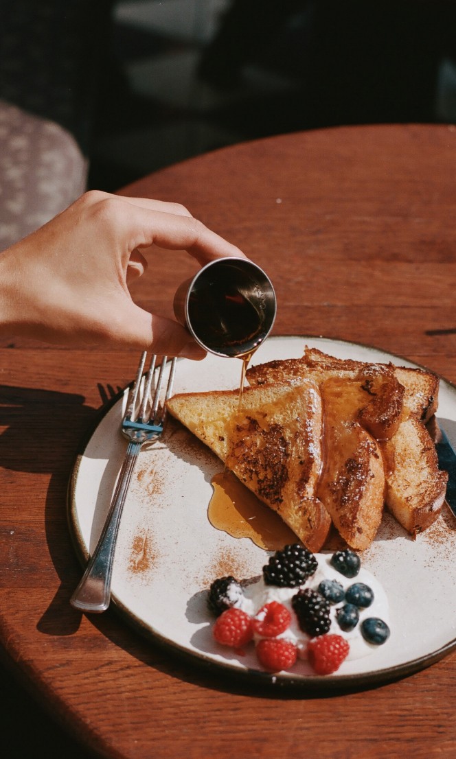 A person pours syrup onto french toast.