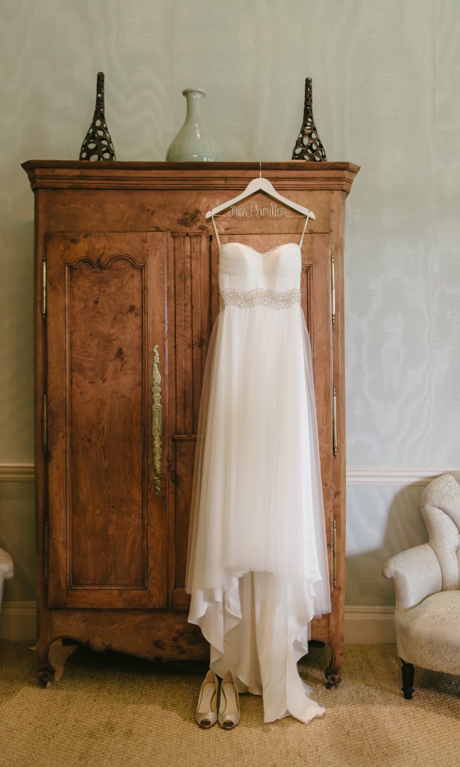 A wedding dress hanging on a wooden wardrobe.