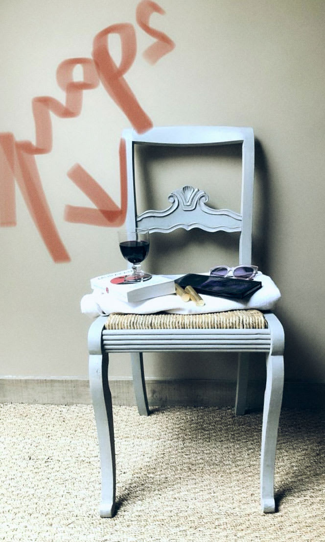 A chair with items on it and props written in red lipstick over it.