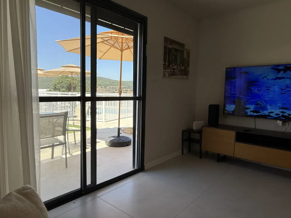 סלון עם טלוויזיה ודלת זכוכית אל החצר
