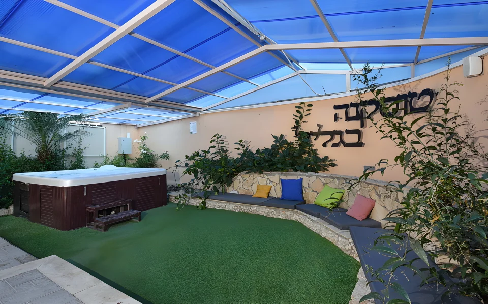 פינת הג'קוזי של וילה טוסקנה, עם ספסל אבן וכריות צבעוניות מתחת לקירוי
