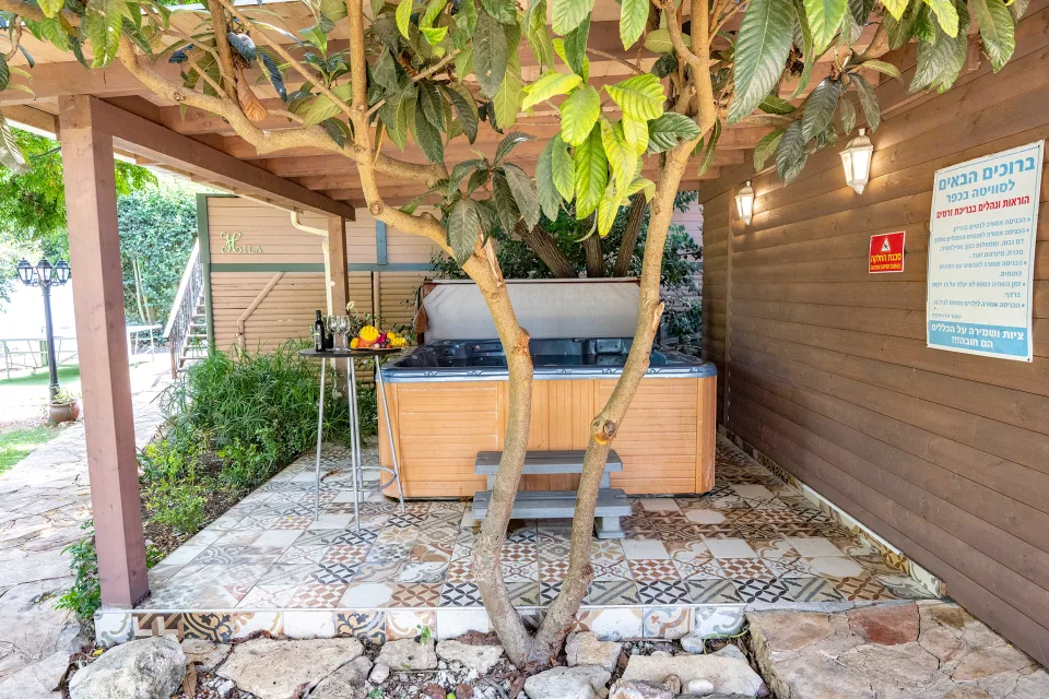 ג'קוזי ספא חיצוני תחת פרגולת עץ עם ריצוף מעוטר בסוויטה בכפר