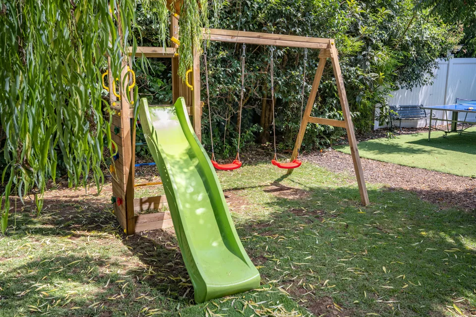 מתקן שעשועים עם מגלשה ונדנדות בגינה של סוויטה בכפר