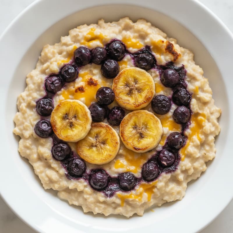 Egg and Cheese Oatmeal Bowl with Sautéed Blueberries and Banana Slices