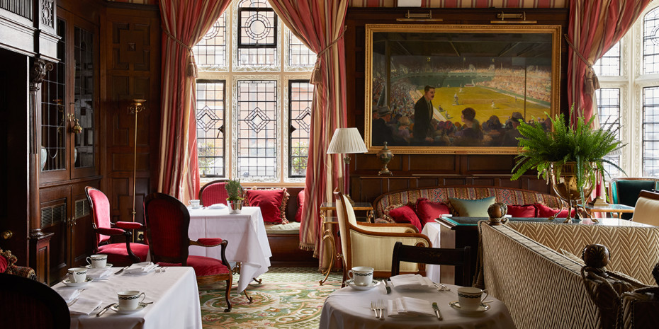 Image of a luxury room with tables set for dining, big curtains and gold framed artwork