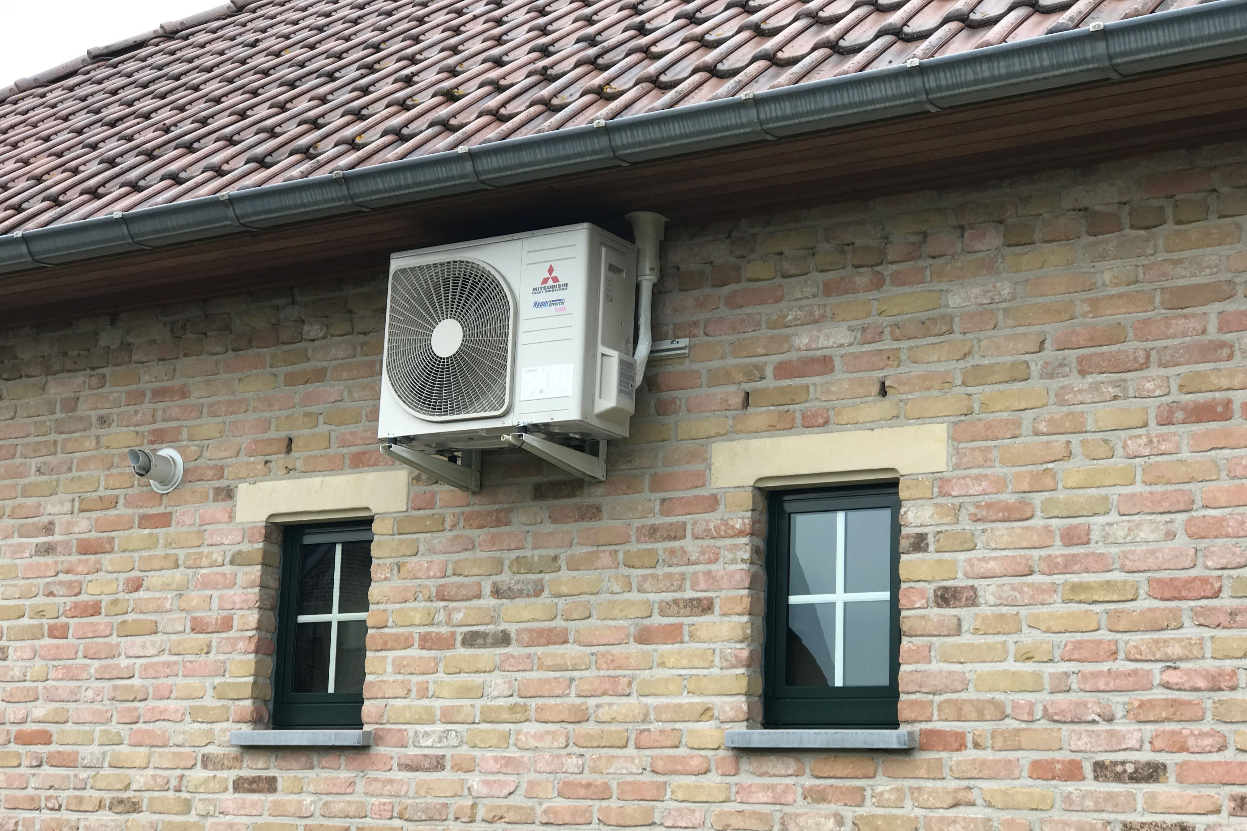 warmtepomp buitenunit aan de zijkant van een buitenmuur