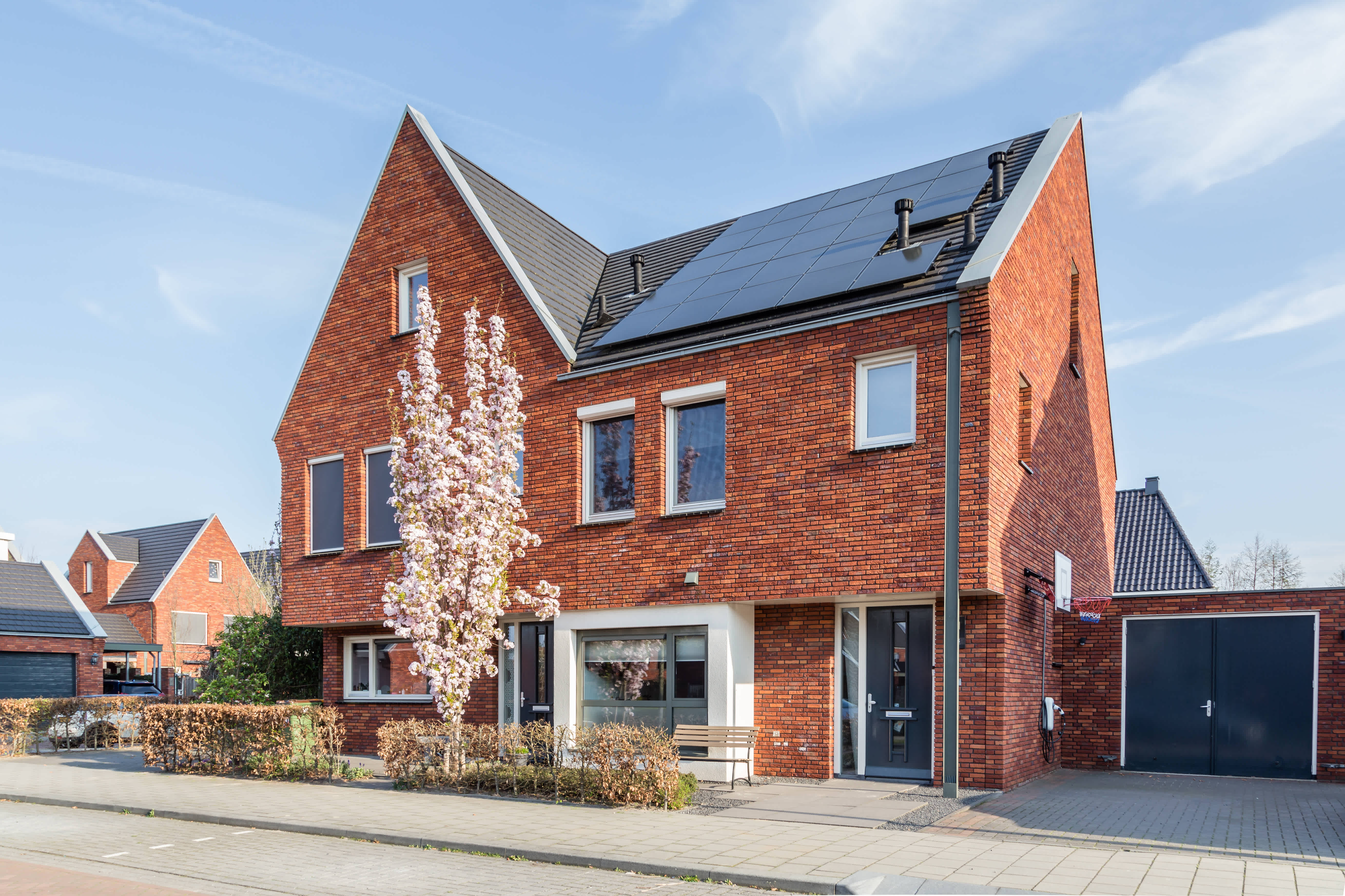Zwarte zonnepanelen op een schuin dak aan straatkant van de woning.