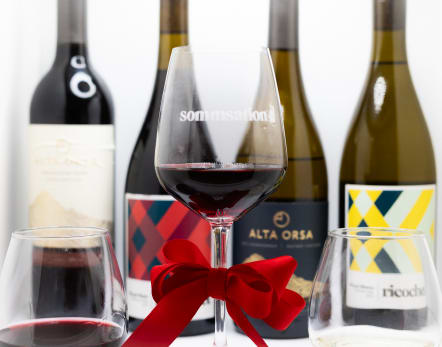 red wine glass with bow, four bottles of wine