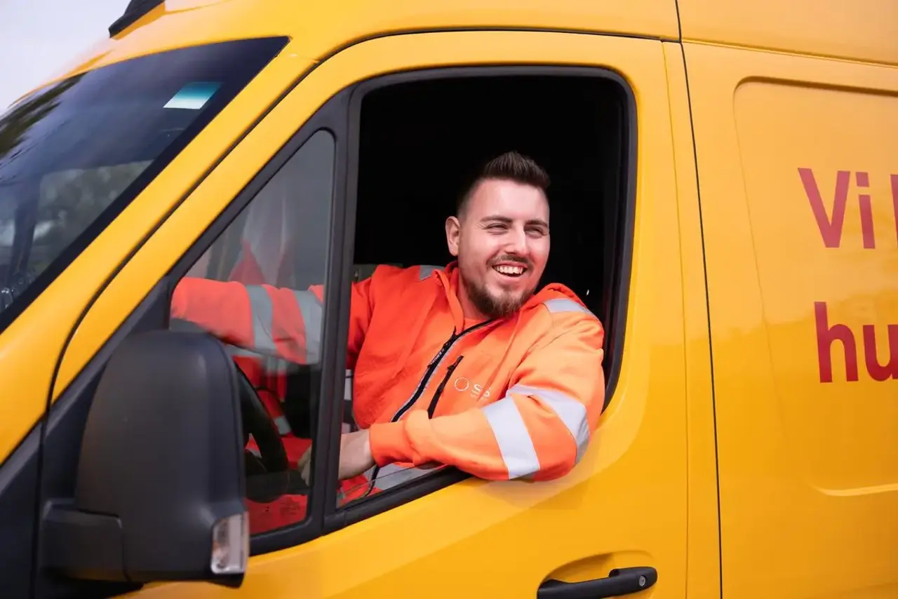 Autoredder sidder i teknikerbil og smiler
