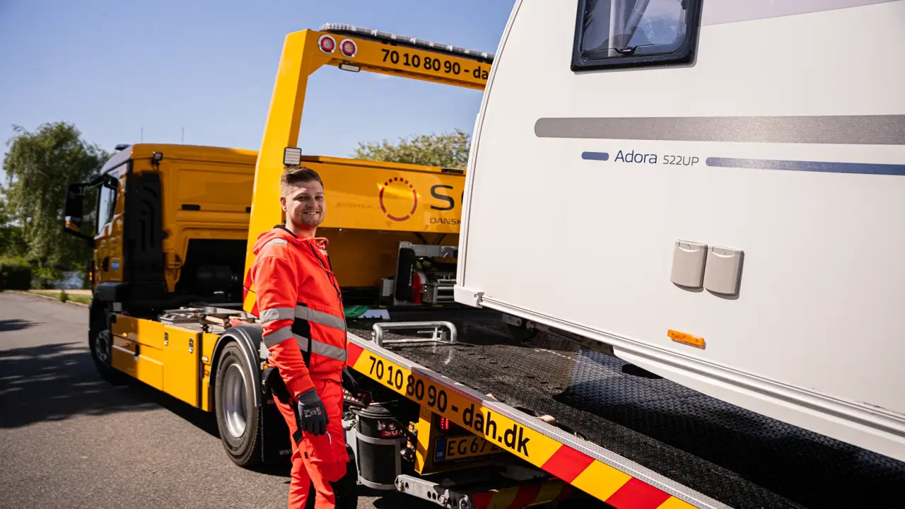 Campingvogn på lad med autoredder ved siden af