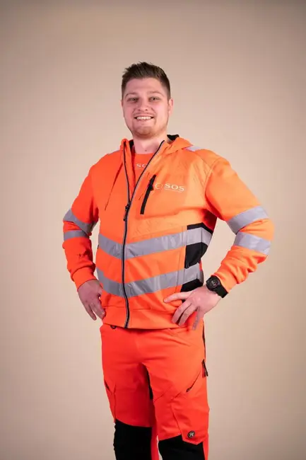 Autoredder står med armene i siden og smiler til kameraet