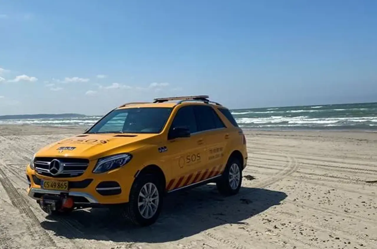 Autoredder bil ses på strand. Billedet taget forfra. I baggrunden ses havet. 