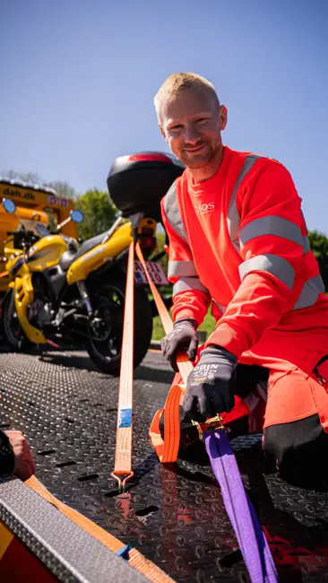 Autoredder sidder på lad med motorcykel