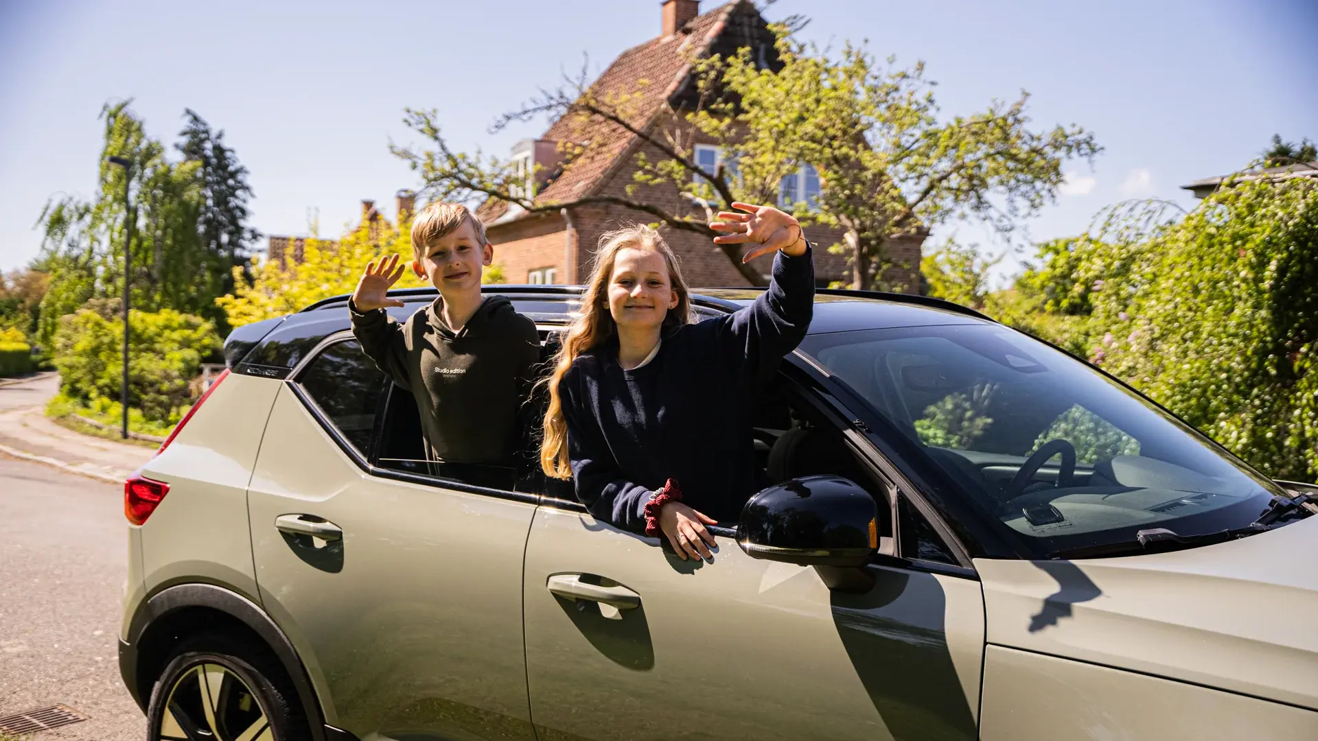 Børn vinker ud af vinduet