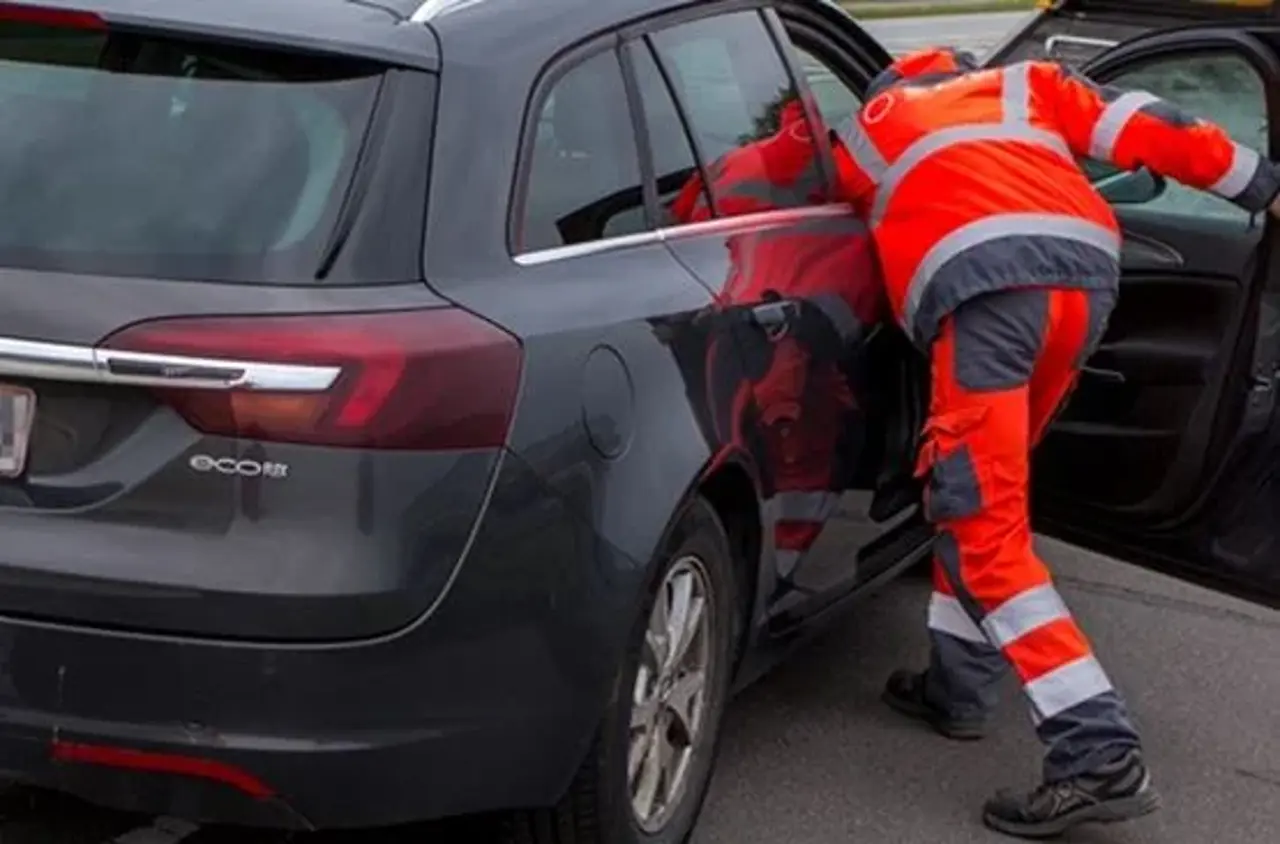 Autoredder står med hovedet inde i bil i passagersiden