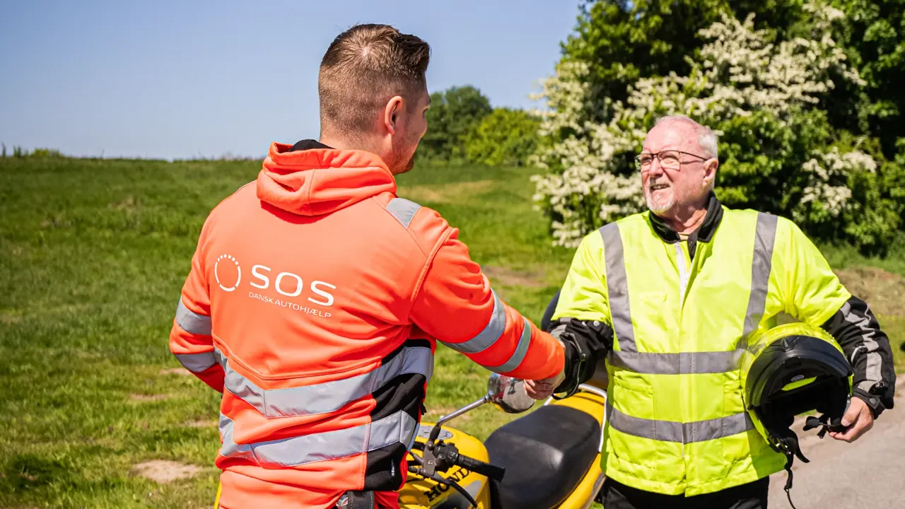 Autoredder og motorcykel ejer giver hånd