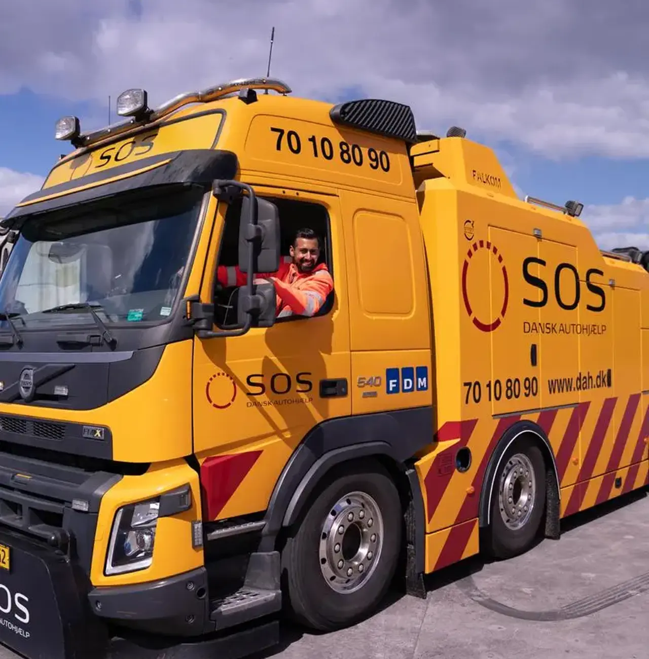 Autoredder sidder i en lastbil og smiler