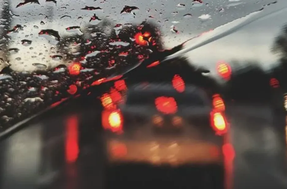 Baglygter ses gennem forrude fyldt med regn