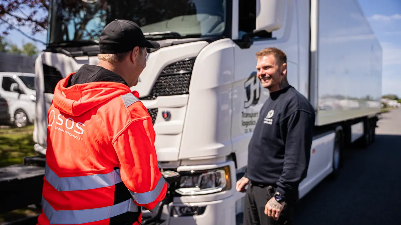 Autoredder står ved siden af lastbilchauffør